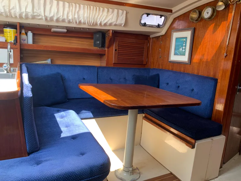 Slide: The Image of Interior of 1987 Catalina 30 Tall-Rig sailboat with blue cushioned seating and wooden table. - 46