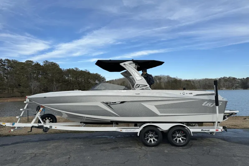 Slide: The Image of 2024 Tigé RZX22 boat on trailer by a lake with trees in the background. - 1