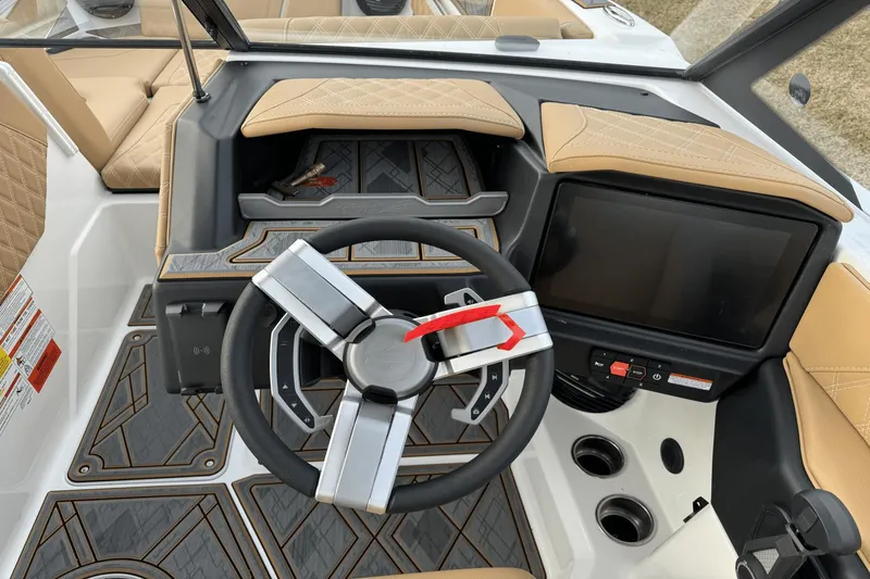 Slide: The Image of 2024 Tigé RZX22 boat dashboard with steering wheel, touchscreen display, and tan upholstery. - 18