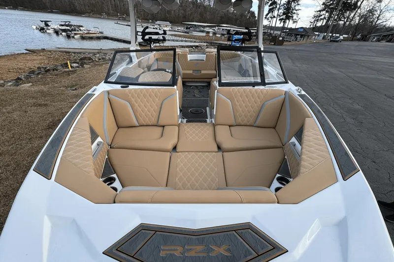 Slide: The Image of 2024 Tigé RZX22 boat interior with tan leather seats, docked by a lake. - 26