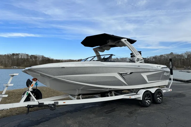 Slide: The Image of 2024 Tigé RZX22 boat on trailer by a lake under a blue sky. - 3