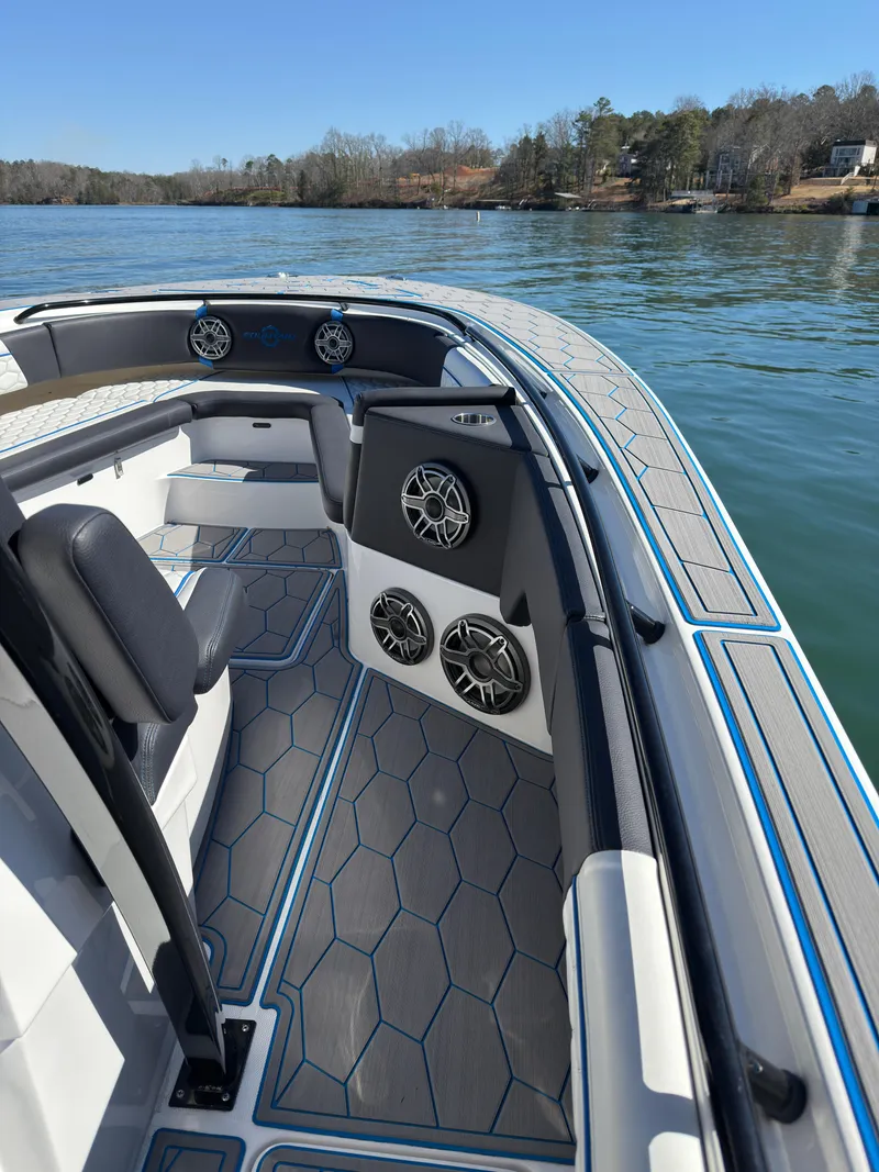 Slide: The Image of 2024 Fountain 34 SC boat interior with sleek seating and modern speaker system on a calm lake. - 7