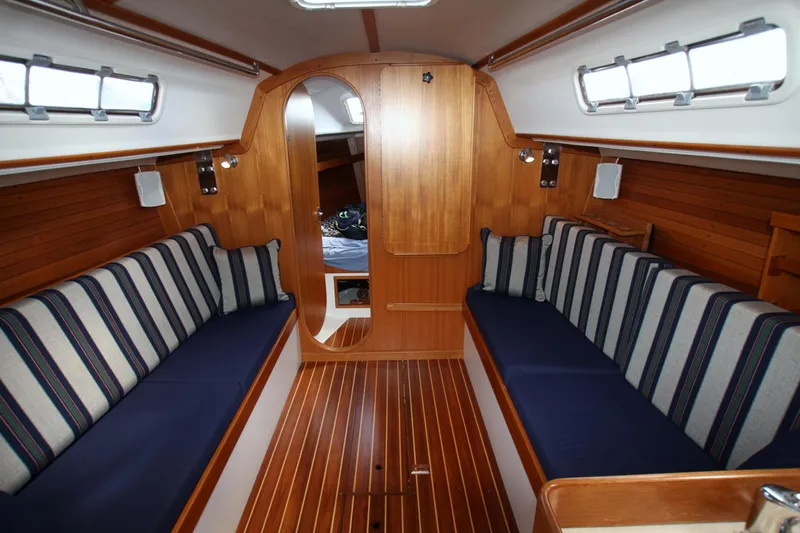 Slide: The Image of Interior of 2001 J Boats 32 sailboat with striped cushions and wooden finishes. - 1