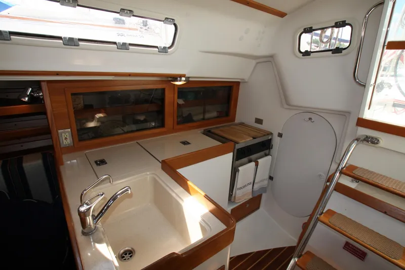 Slide: The Image of Interior of 2001 J Boats 32 sailboat, featuring compact kitchen with sink and wooden cabinetry. - 31