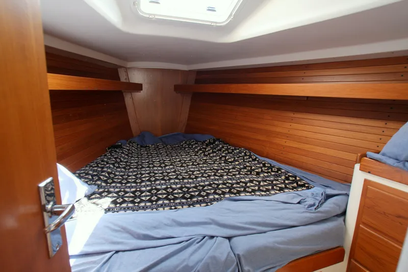 Slide: The Image of Cozy cabin interior of 2001 J Boats 32, featuring wooden paneling and a patterned bedspread. - 36
