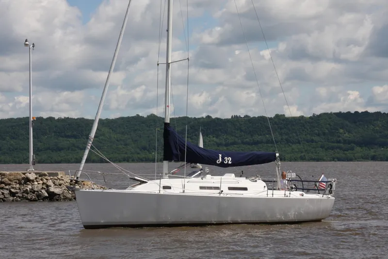 Slide: The Image of 2001 J Boats 32 sailboat docked on a calm lake under a cloudy sky. - 4