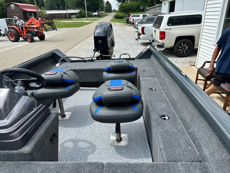 Slide: The Image of 2024 Ranger VS1665SC fishing boat with seating and motor, parked near trucks and a tractor. - 9