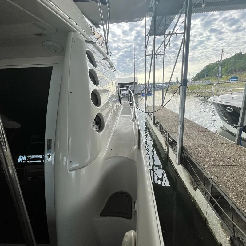 Slide: The Image of 2002 Regal Commodore 3880 yacht docked at a marina under a cloudy sky. - 11
