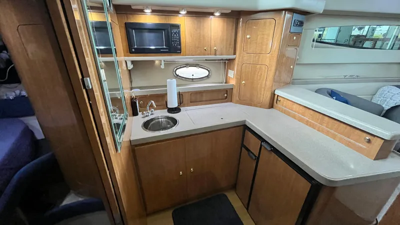 Slide: The Image of 2002 Regal Commodore 3880 yacht kitchen with microwave, sink, and wooden cabinetry. - 22