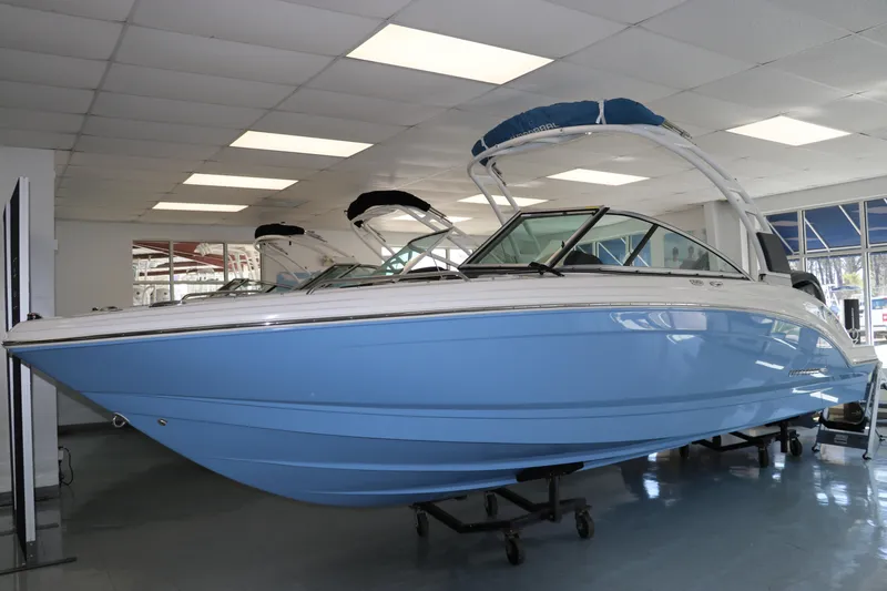 The Image of 2024 Chaparral 23 SSi OB boat in showroom, featuring sleek blue hull design. - 0