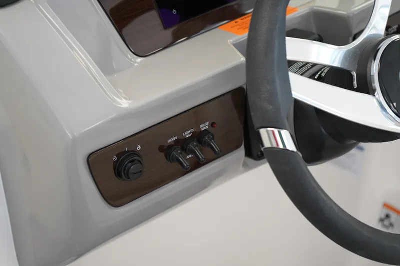 Slide: The Image of 2024 Chaparral 23 SSi OB boat dashboard with steering wheel and control switches. - 26