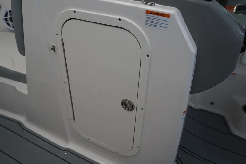 Slide: The Image of 2024 Chaparral 23 SSi OB boat storage compartment with secure latch and warning label. - 28