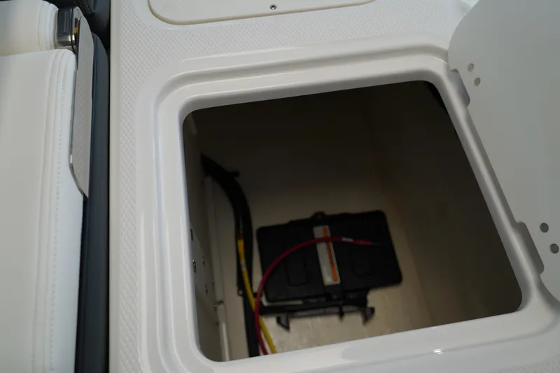Slide: The Image of 2024 Chaparral 23 SSi OB boat storage compartment with visible battery and wiring. - 8
