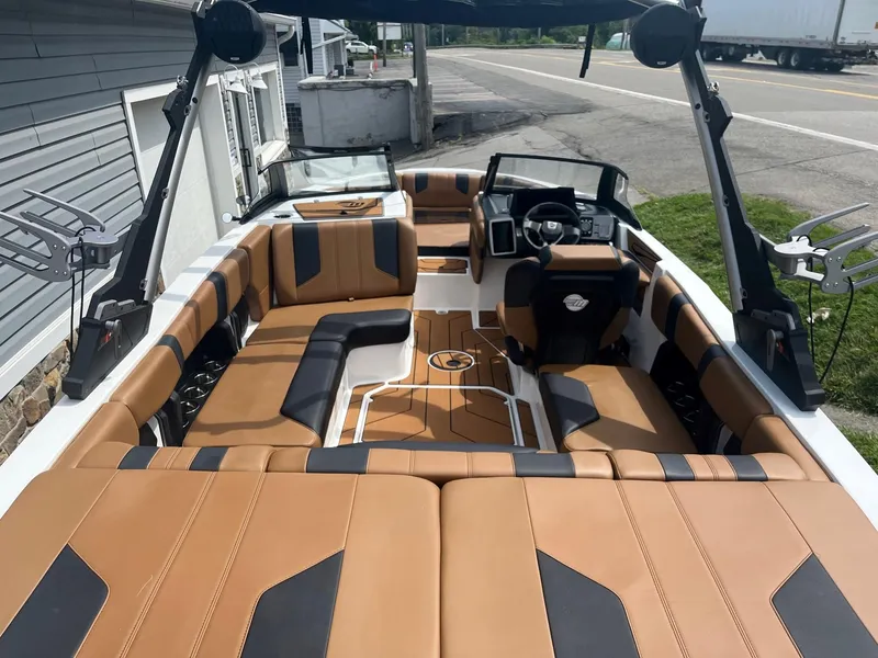 Slide: The Image of 2024 Malibu 21 LX boat with tan and black interior, docked near a road. - 4