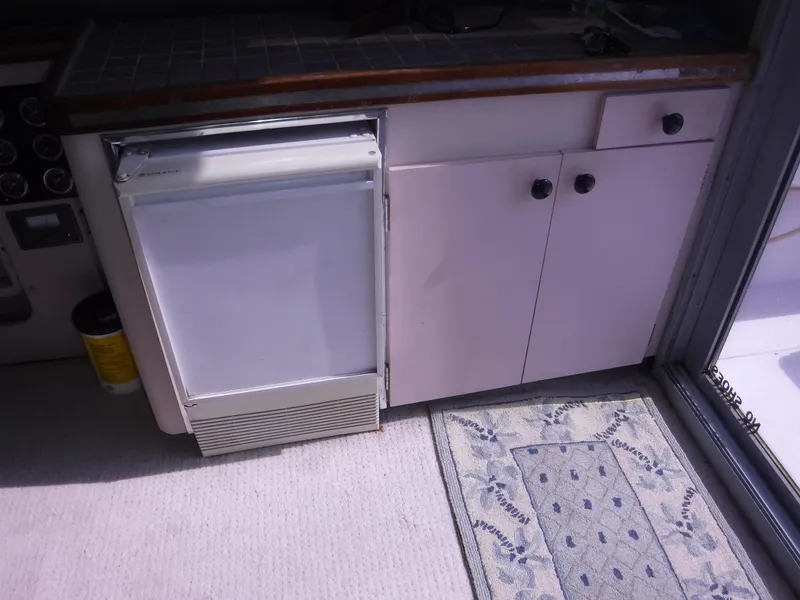 Slide: The Image of 1988 Trojan 12 Meter yacht interior with fridge, cabinets, and patterned rug. - 15