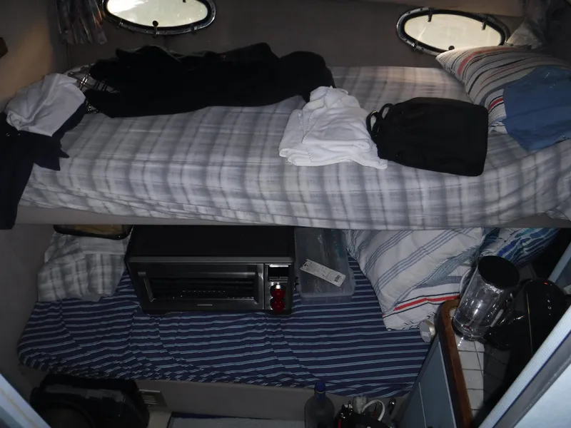 Slide: The Image of Interior of a 1988 Trojan 12 Meter boat with bunk beds and personal items. - 19