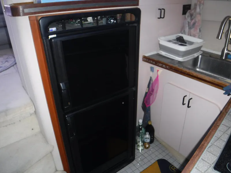 Slide: The Image of 1988 Trojan 12 Meter yacht kitchen with black fridge, sink, and cabinets. - 22