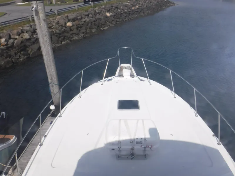 Slide: The Image of 1988 Trojan 12 Meter yacht bow view at dockside, calm water, and rocky shoreline. - 27