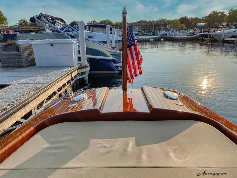 Slide: The Image of Custom 2020 Windlea Runabout boat docked, featuring American flag and polished wood finish. - 28