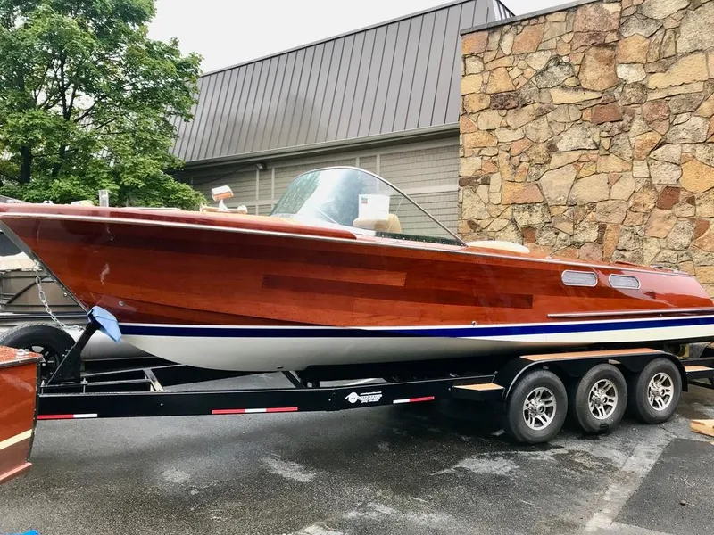 Slide: The Image of Custom 2020 Windlea Runabout boat on trailer, featuring sleek wooden design and triple-axle support. - 33