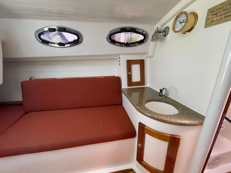 Slide: The Image of 2008 Schock Harbor 25 interior with red seating, portholes, and compact sink. - 12