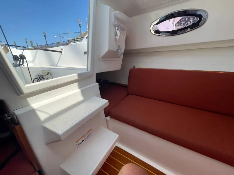 Slide: The Image of Interior of 2008 Schock Harbor 25 sailboat with red seating and wooden flooring. - 13