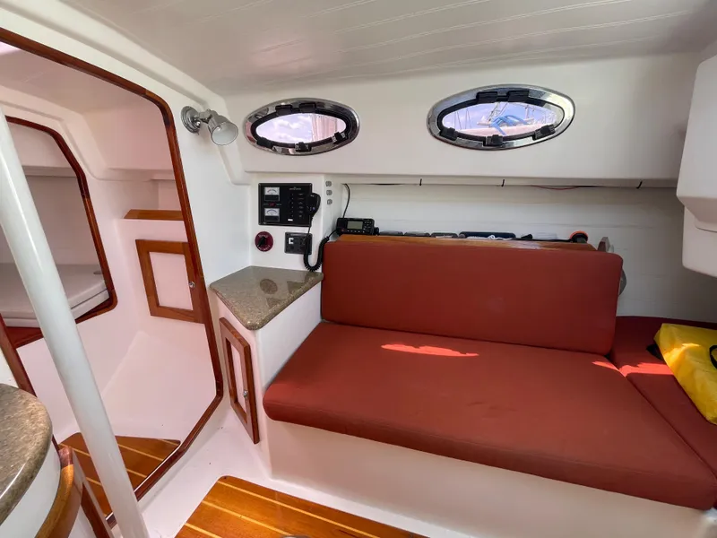 Slide: The Image of Interior of 2008 Schock Harbor 25 sailboat with red seating and wooden accents. - 9