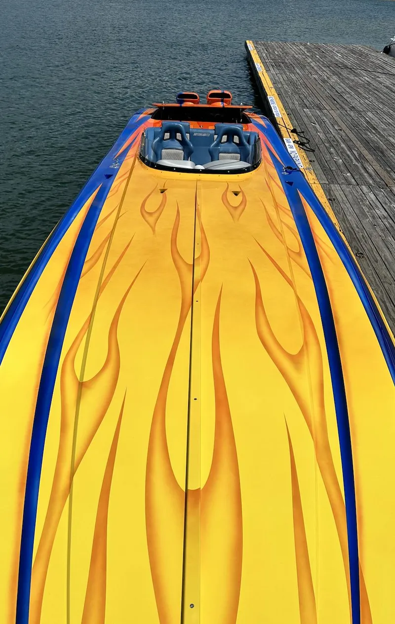 Slide: The Image of 2003 Outerlimits 42 GTX speedboat with vibrant flame design docked by the water. - 10