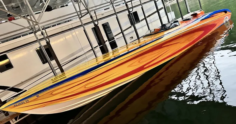 Slide: The Image of 2003 Outerlimits 42 GTX speedboat with vibrant orange and yellow design docked in marina. - 12