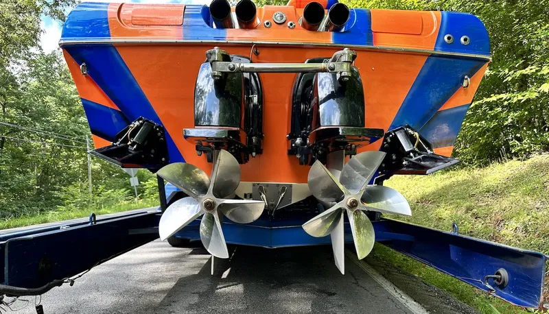 Slide: The Image of 2003 Outerlimits 42 GTX boat rear view with dual propellers and vibrant orange-blue design. - 13