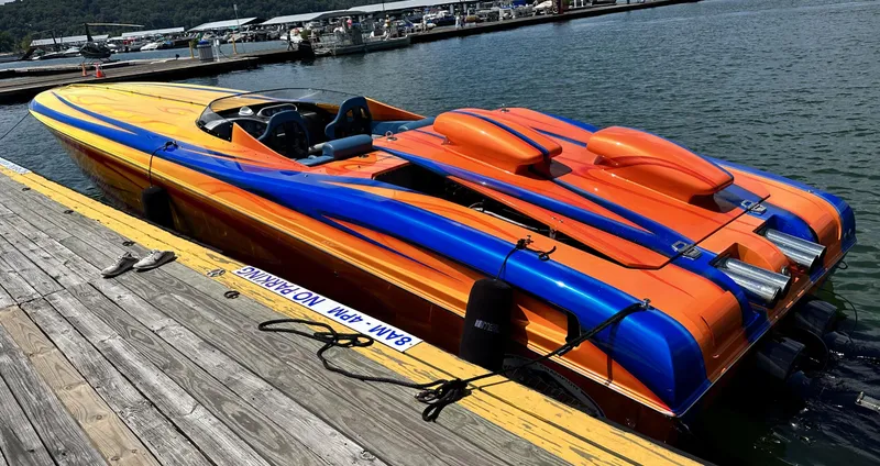 Slide: The Image of 2003 Outerlimits 42 GTX speedboat docked, vibrant orange and blue design. - 7