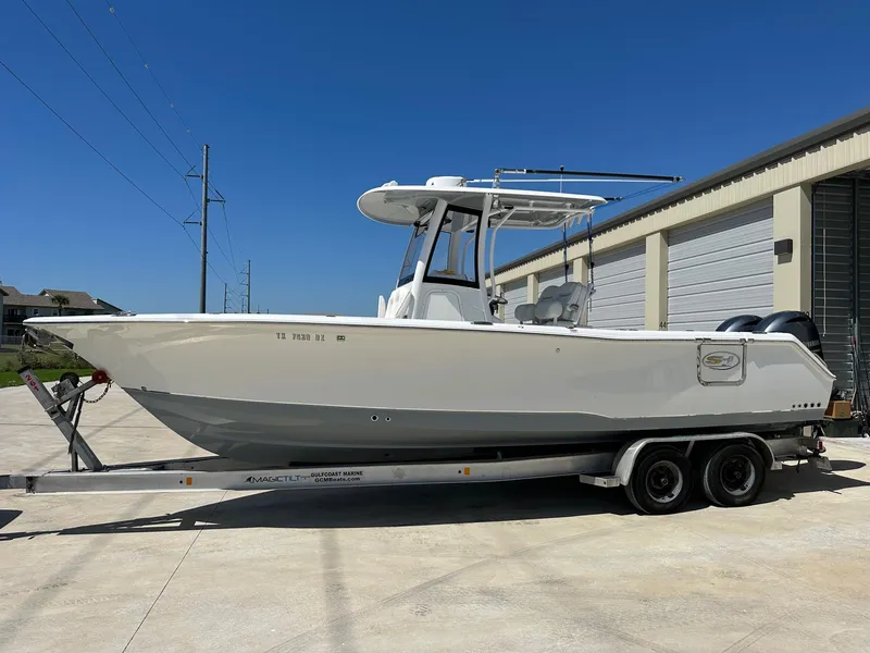 Slide: The Image of 2018 Sea Hunt GAMEFISH 27 CB boat on a trailer, parked outdoors. - 1