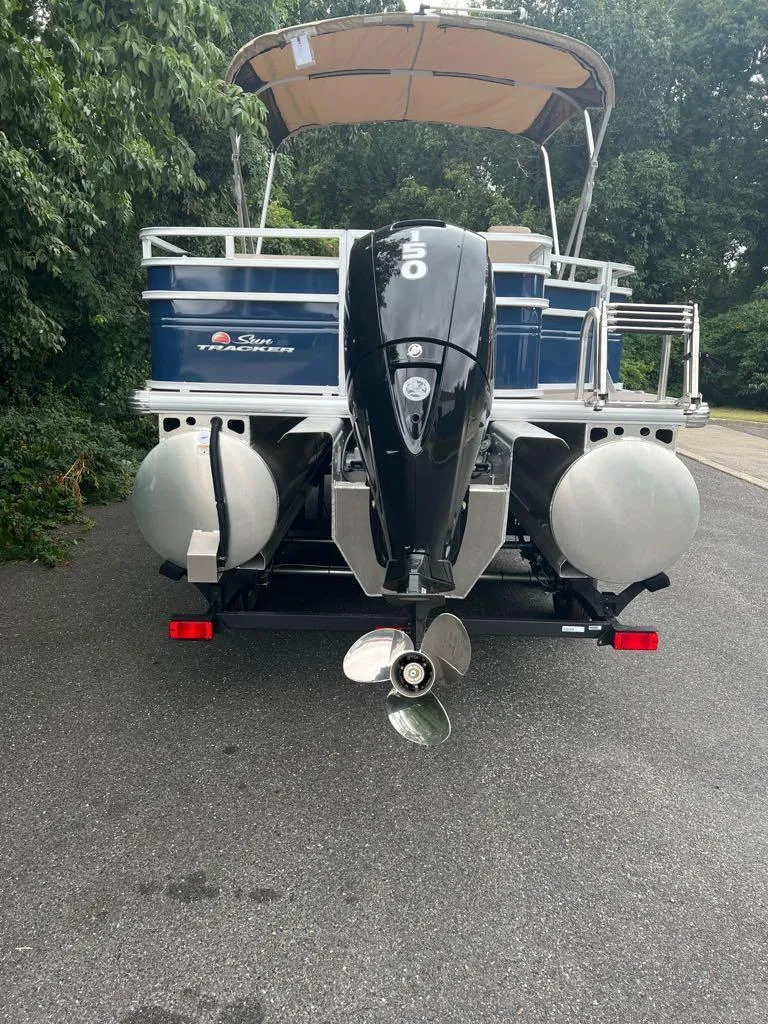 Slide: The Image of 2024 Sun Tracker Fishin' Barge 22 XP3 pontoon boat, rear view with motor and canopy. - 3
