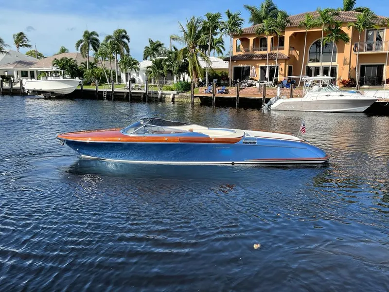 The Image of 2012 Riva Aquariva Super boat cruising on a sunny waterfront with luxury homes. - 0