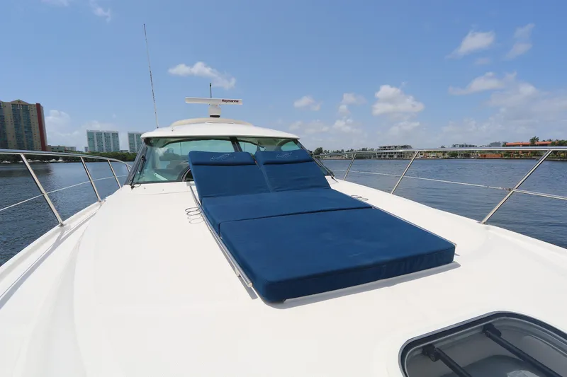 Slide: The Image of 2013 Sea Ray 410 Sundancer yacht with blue sun loungers on deck, docked by waterfront buildings. - 21