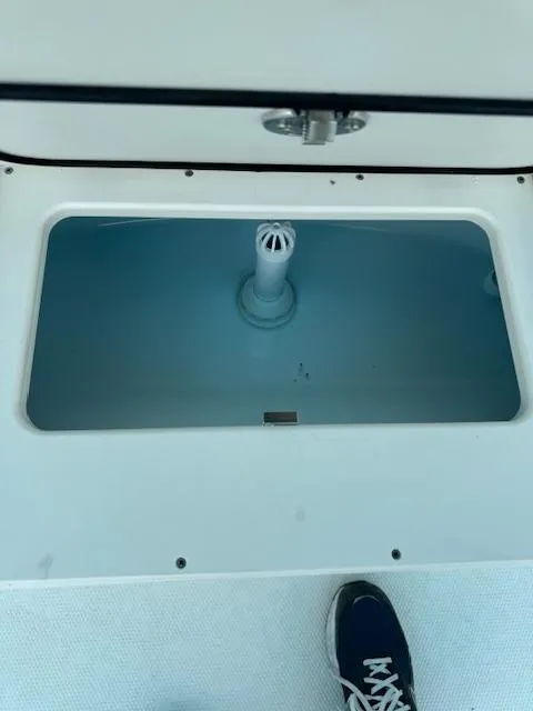 Slide: The Image of 2024 Robalo 270 CC livewell interior with open lid and visible drain. - 12