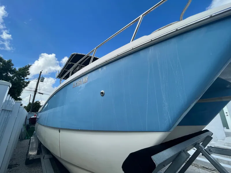 Slide: The Image of 2004 World Cat 270 SF boat on trailer, blue and white hull, clear sky background. - 11