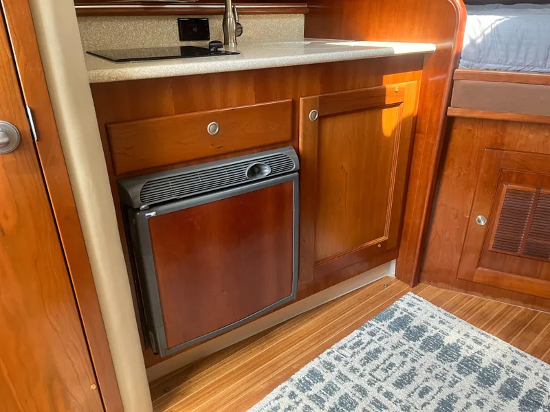 Slide: The Image of 2008 Rampage 30 Express boat interior with wooden cabinetry and compact kitchen area. - 8