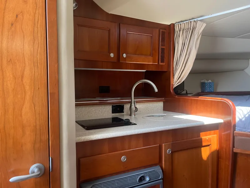 Slide: The Image of 2008 Rampage 30 Express boat interior with wooden cabinets and compact kitchen area. - 9