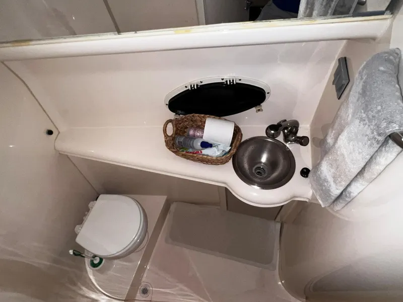 Slide: The Image of 2001 Larson 270 boat bathroom with sink, toilet, and storage basket. - 16