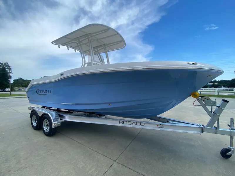 Slide: The Image of 2024 Robalo 202 EXPLORER boat on a trailer, side view, blue hull, white top. - 2