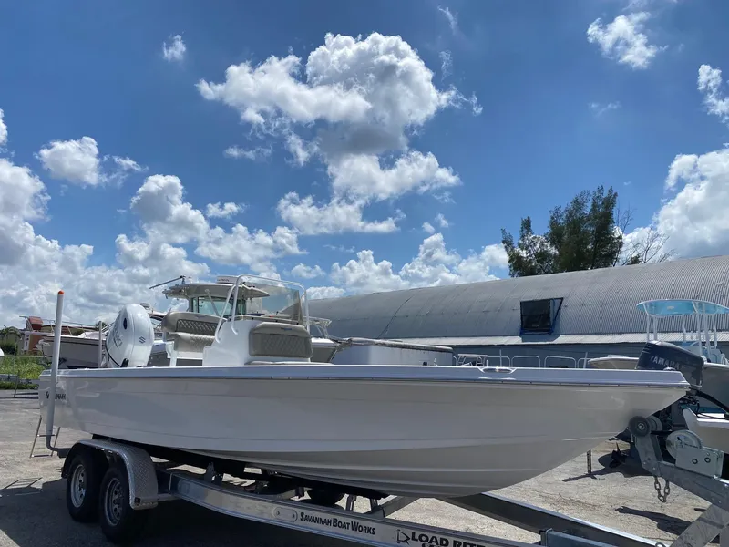 Slide: The Image of 2024 Savannah 220 IS boat on a trailer under a blue sky with clouds. - 3