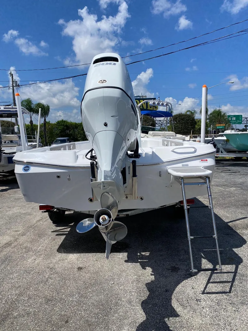 Slide: The Image of 2024 Savannah 220 IS boat with outboard motor and ladder, parked on a sunny day. - 4