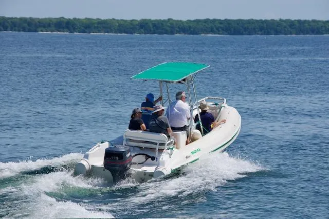 The Image of 1998 Nautica RIB 18 Widebody boat cruising on a lake with passengers. - 1