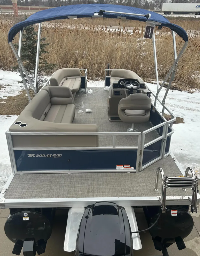 Slide: The Image of 2024 Ranger Reata 200C pontoon boat with blue canopy and spacious seating. - 2
