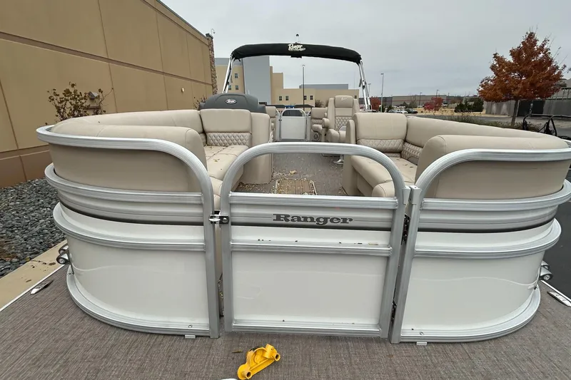 Slide: The Image of 2023 Ranger Reata 243C pontoon boat with beige seating and open gate. - 2