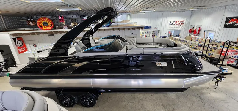 Slide: The Image of 2024 Bennington 25QXSBA pontoon boat in showroom, black exterior, luxury seating. - 0