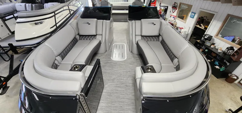 Slide: The Image of 2024 Bennington 25QXSBA pontoon boat interior with luxurious seating in showroom. - 3
