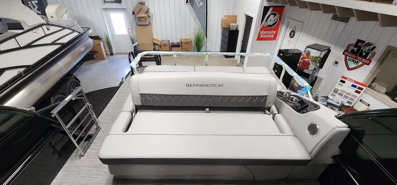 Slide: The Image of 2024 Bennington 25QXSBA boat interior with a spacious, luxurious seating area in a showroom. - 5