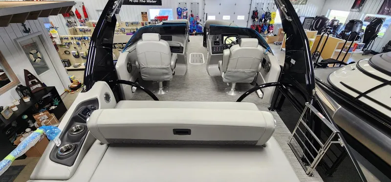 Slide: The Image of 2024 Bennington 25QXSBA boat interior with seating and helm station in showroom. - 8